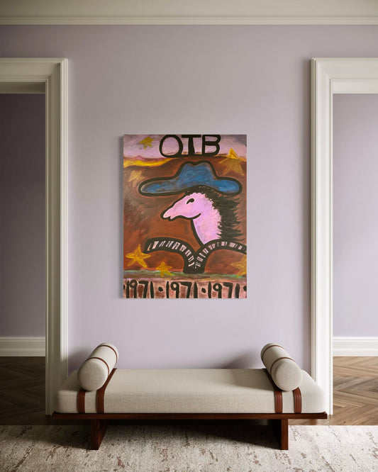 A framed wall art print featuring a stylized pink horse head with a blue hat and the text 'OTB' and '1971 1971 1971', displayed on a lavender-gray wall above a cream upholstered bench in a modern interior.